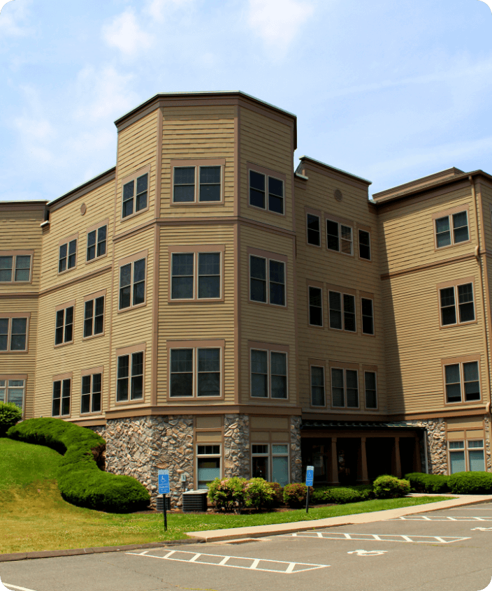 photo of a yellow, four story building with a parking lot in front.